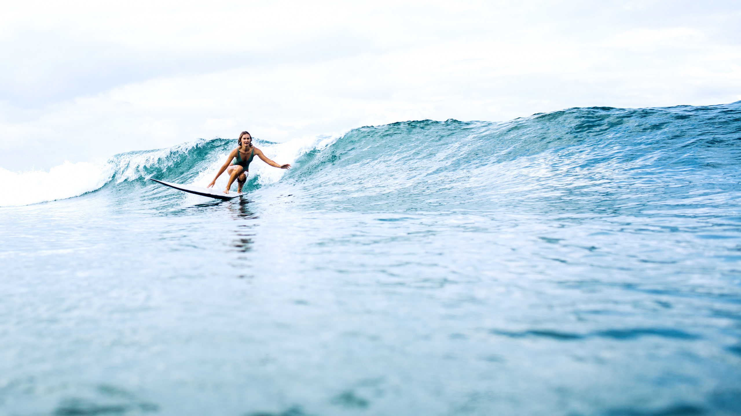 beautiful surfer girl riding on a board in the ocean on bali island
